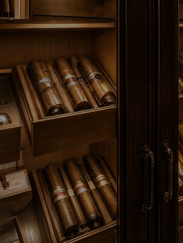 An open drawer of cigars in a timber cabinet, lit from within