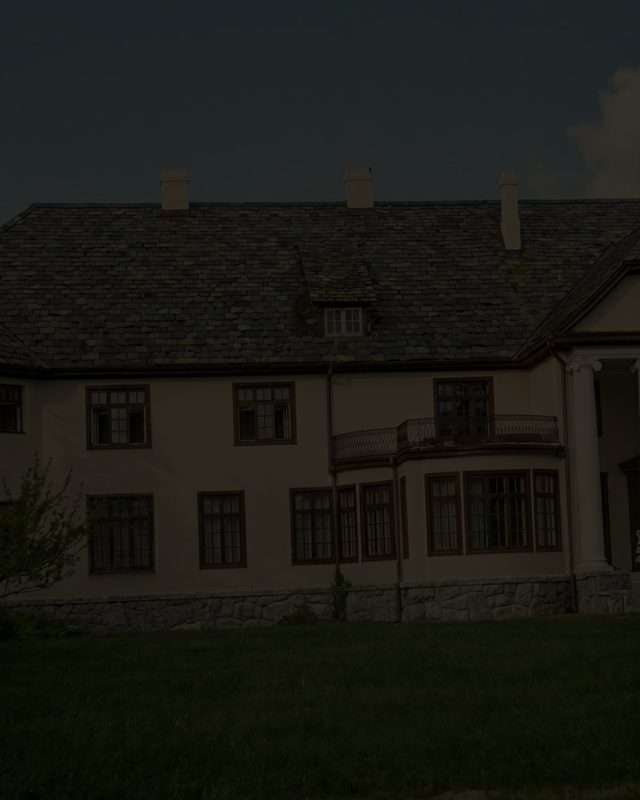 The garden front of the manor house above its lawn at dusk
