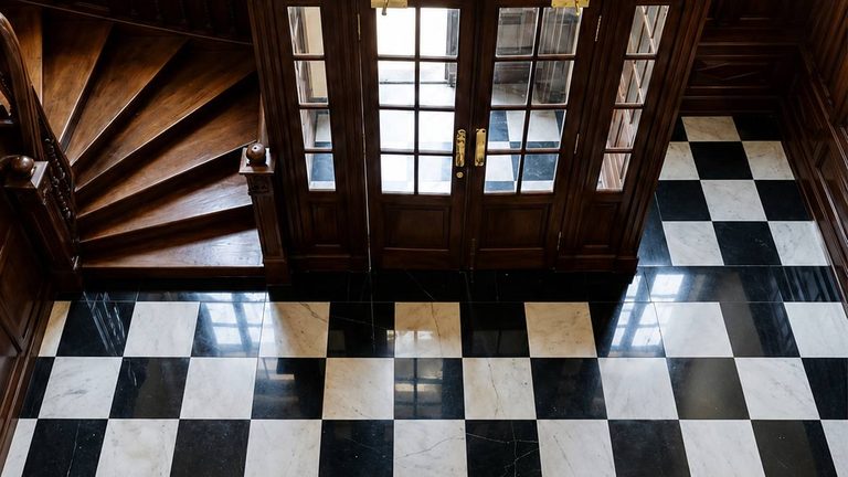 The chequered marble floor of the hall, seen from the landing above it
