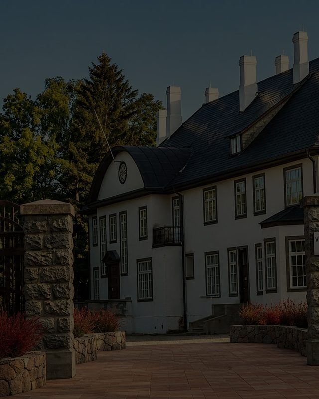 The manor house from the lawn, its roof and chimneys above the trees