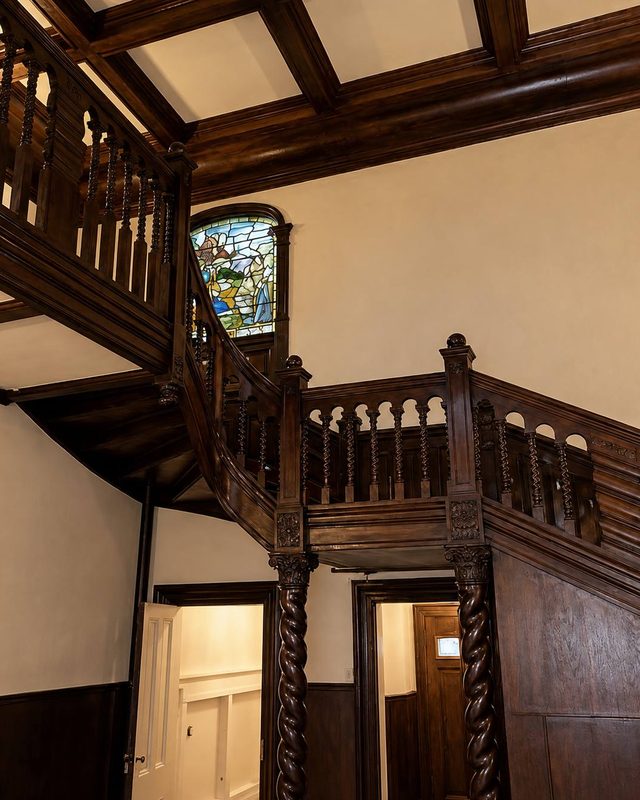 The turn of the main staircase, its stained glass window above