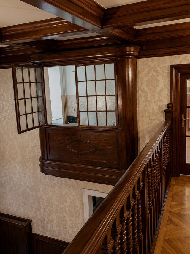 A glazed timber window set into an interior wall above the stair, its casement standing open